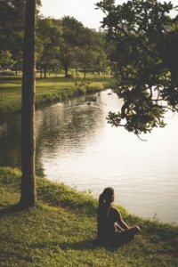 woman-sitting-on-grass-by-lake-290627